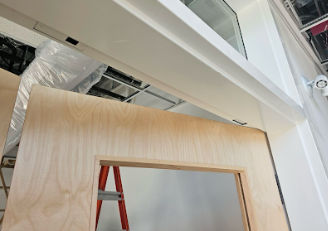 Interior door frame with concealed overhead stop mechanism discretely integrated into the frame header.