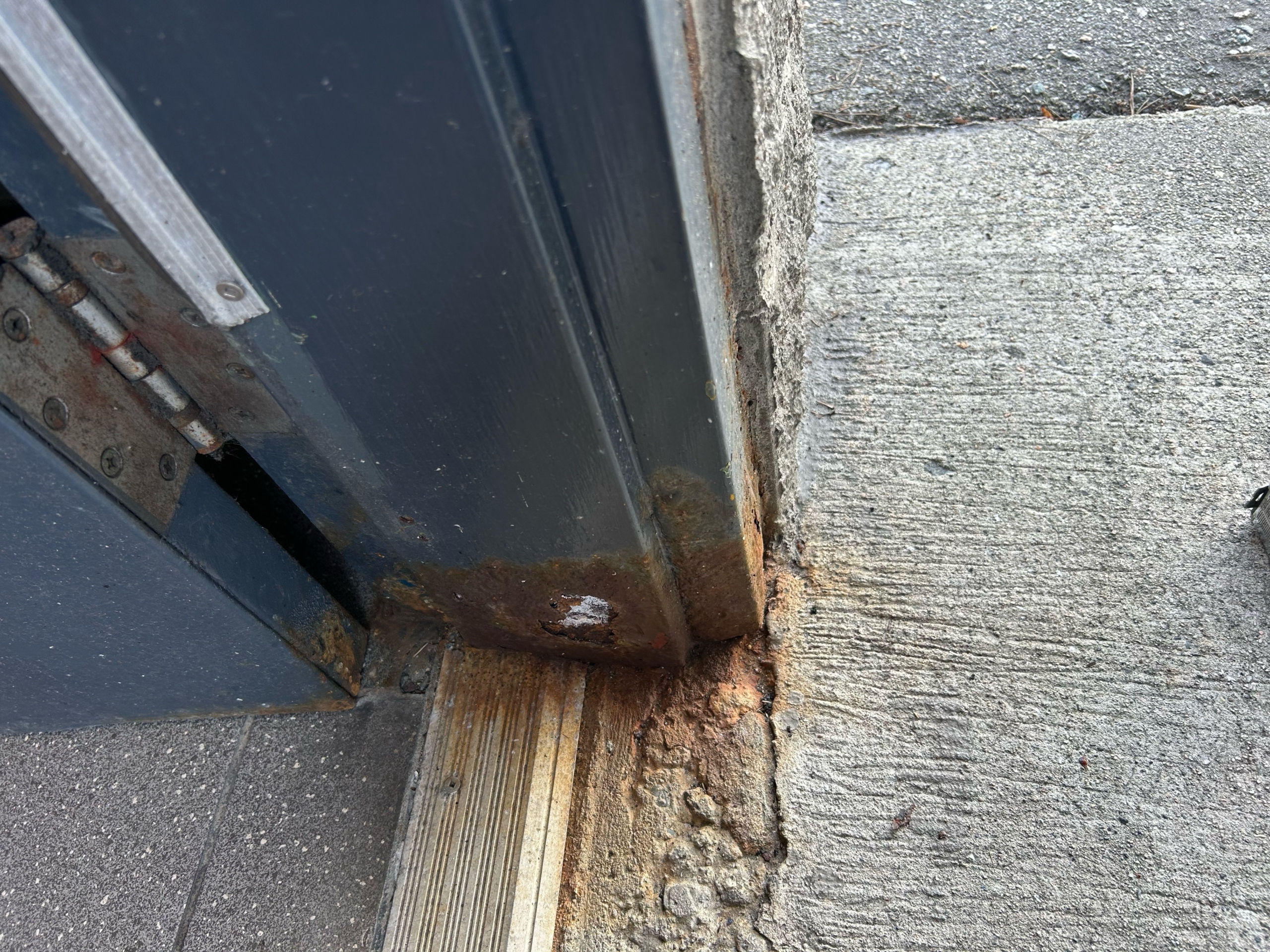 Bottom hinge area with rust and damage to threshold and frame