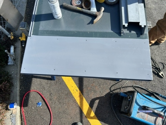 Freshly primed steel door header on workbench with tools nearby.