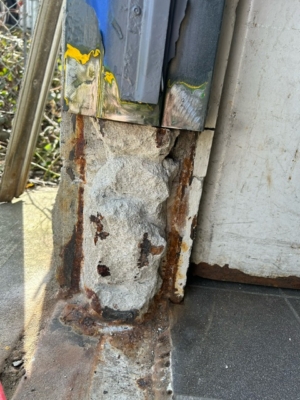 everely corroded and crumbling steel door frame base