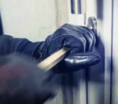 Gloved hand using a crowbar to force open a commercial door lock