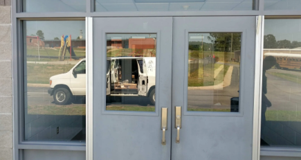 Double aluminum entry doors with continuous hinges and pull handles at commercial building entrance