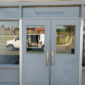 Double aluminum entry doors with continuous hinges and pull handles at commercial building entrance