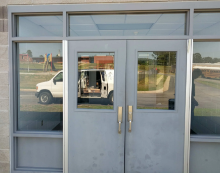 Double aluminum entry doors with continuous hinges and pull handles at commercial building entrance