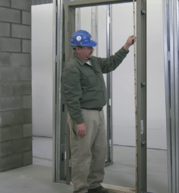 Technician inspecting a hollow metal door frame during commercial door installation in Vancouver.
