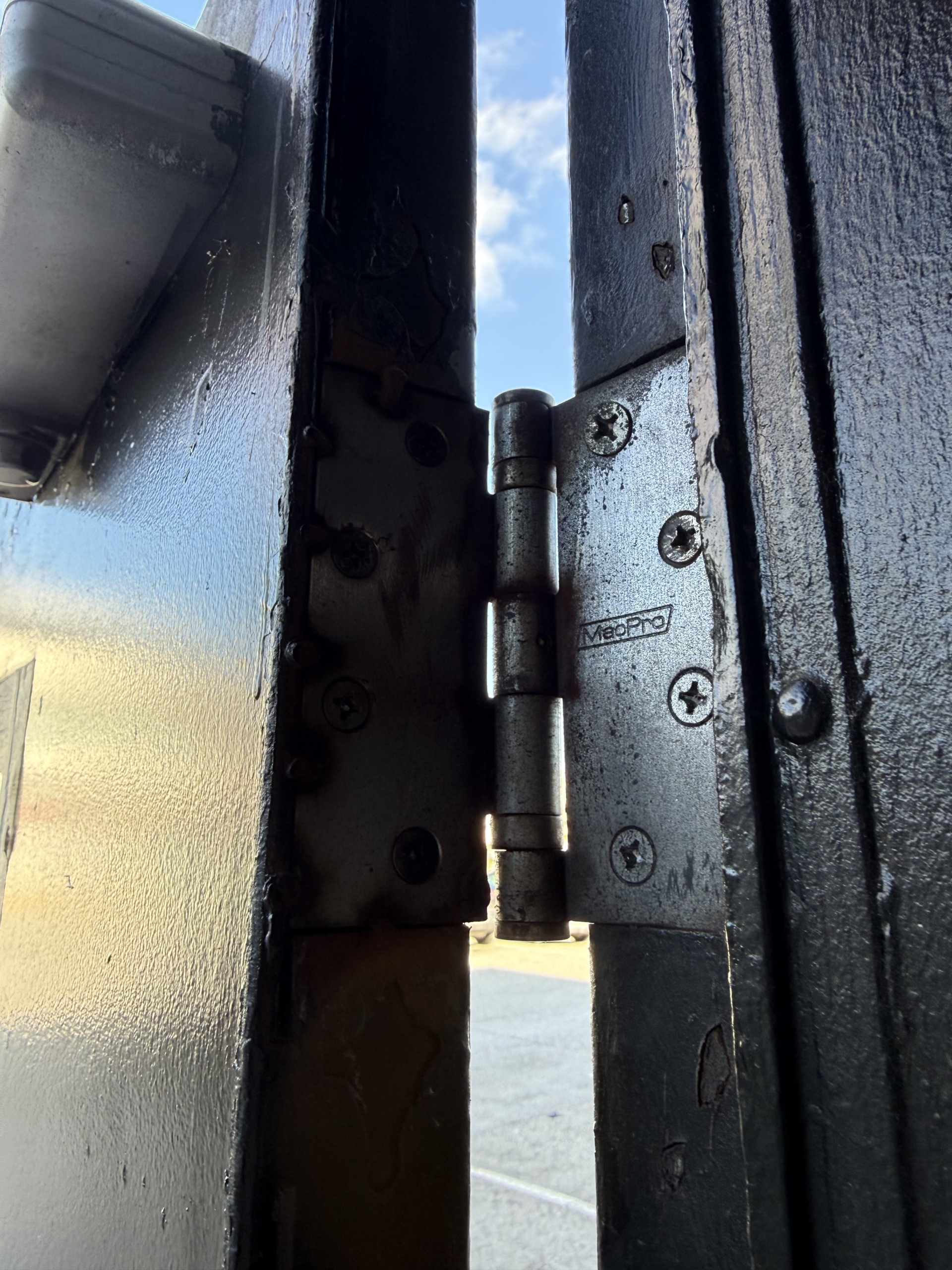 Existing commercial steel door hinge before hardware repair