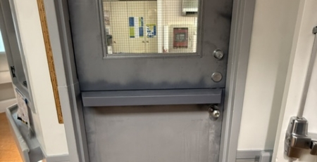 Gray commercial steel Dutch door with a vision panel in the upper section, viewed from a service area.