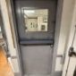 Gray commercial steel Dutch door with a vision panel in the upper section, viewed from a service area.