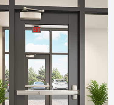 Commercial glass entrance door with overhead door closer and panic exit bar.